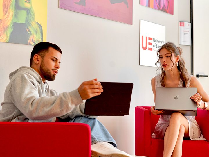 a man and a woman sitting on a couch looking at a laptop